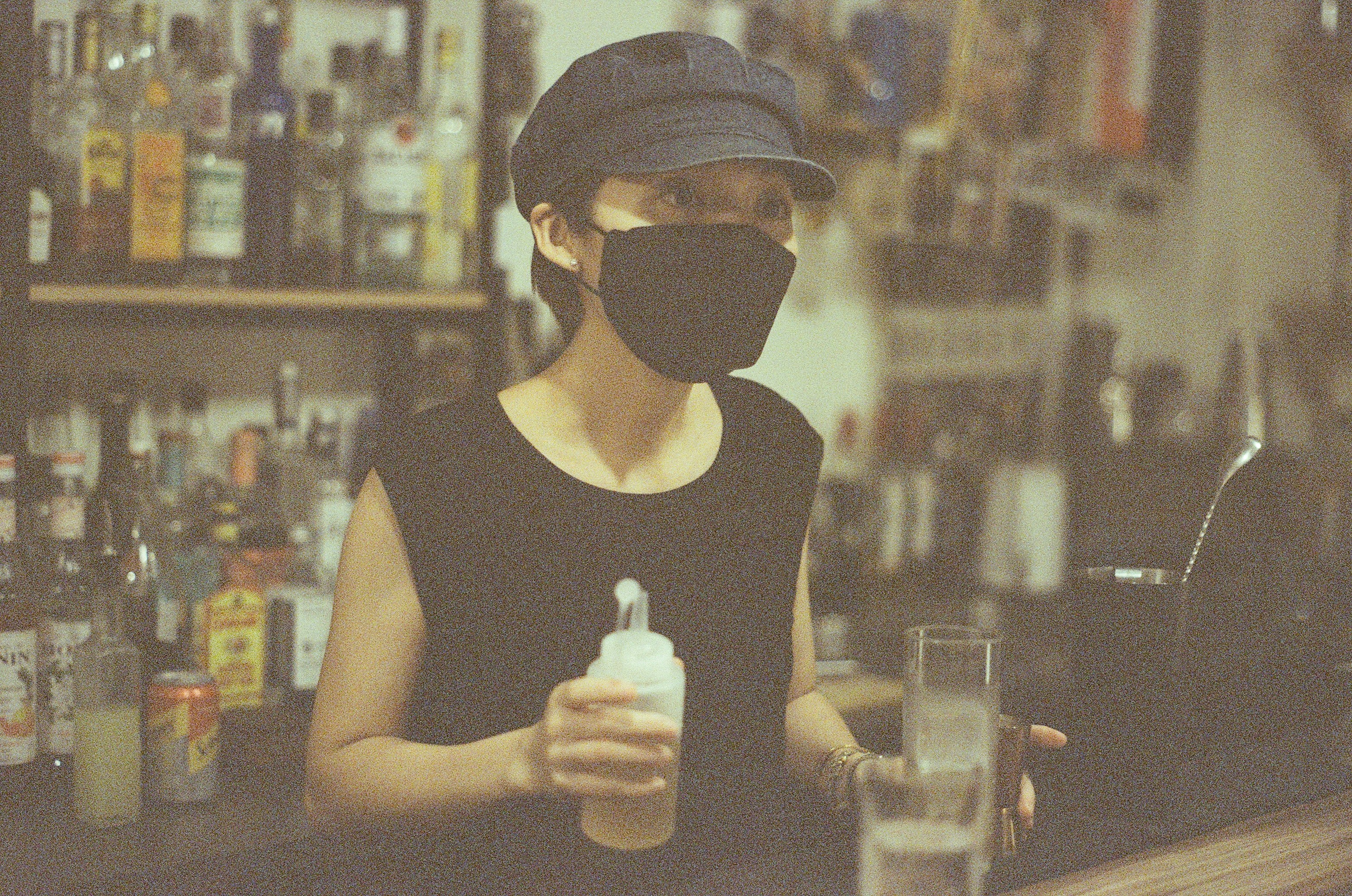 Masked bartender behind a bar
