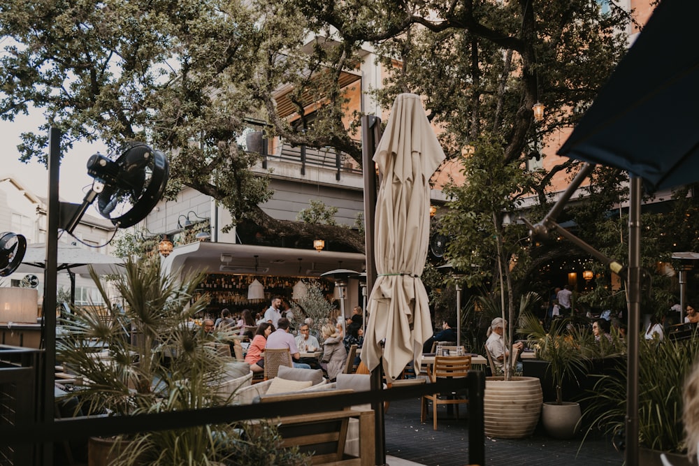 a group of people sitting at tables under umbrellas