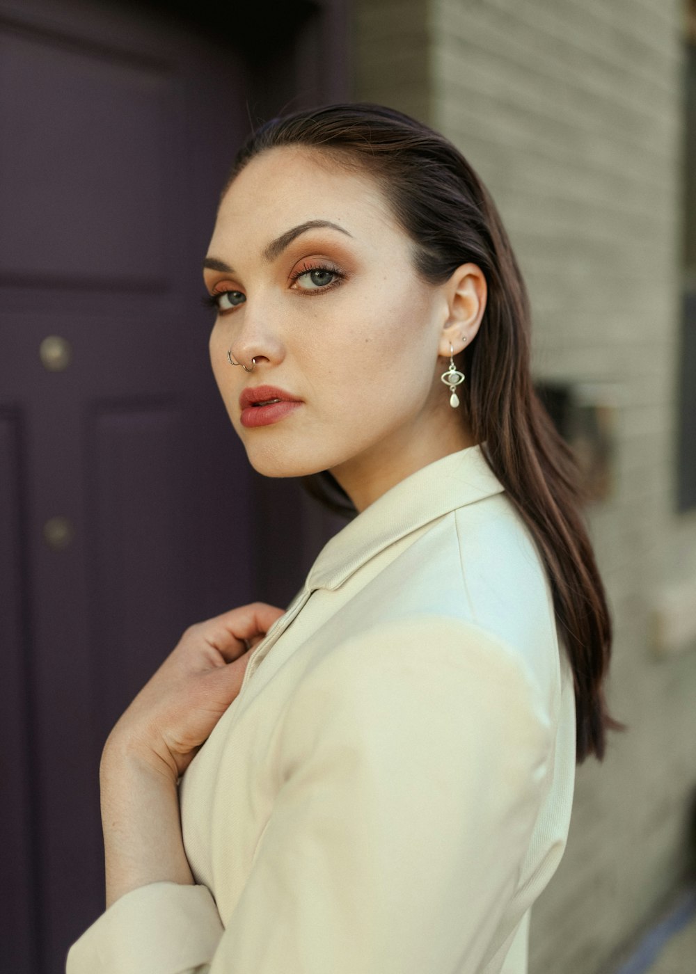 a woman in a white jacket and earrings