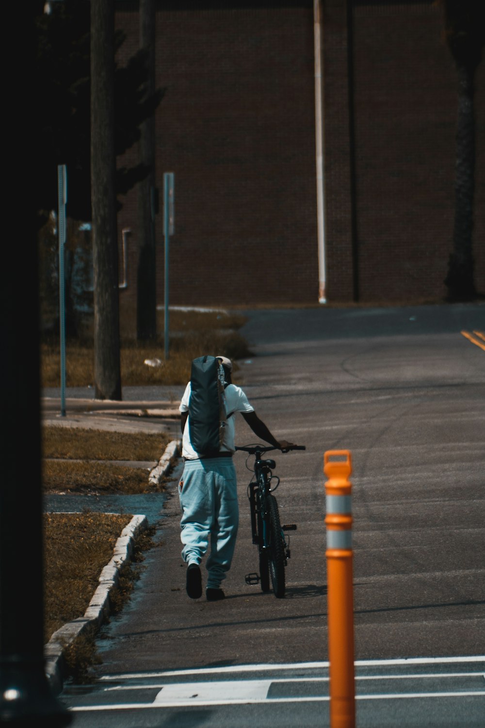 a person with a backpack walking a bike down a street