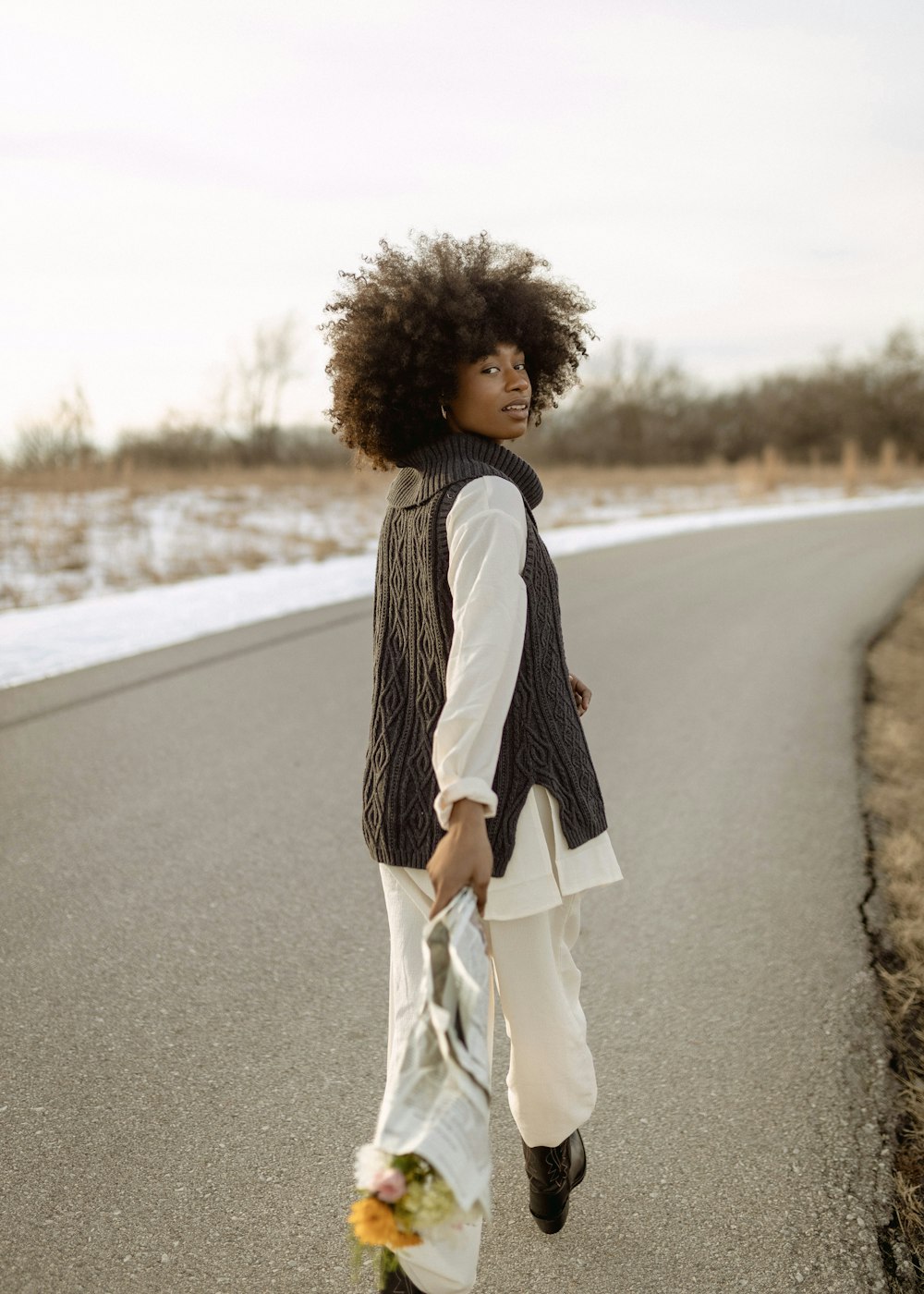 Une femme marchant sur une route portant un sac