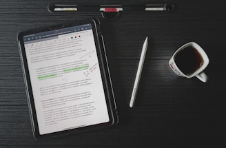 a tablet computer sitting on top of a desk next to a cup of coffee