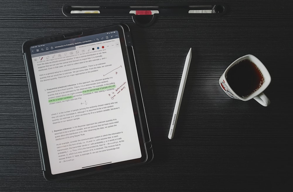 a tablet computer sitting on top of a desk next to a cup of coffee