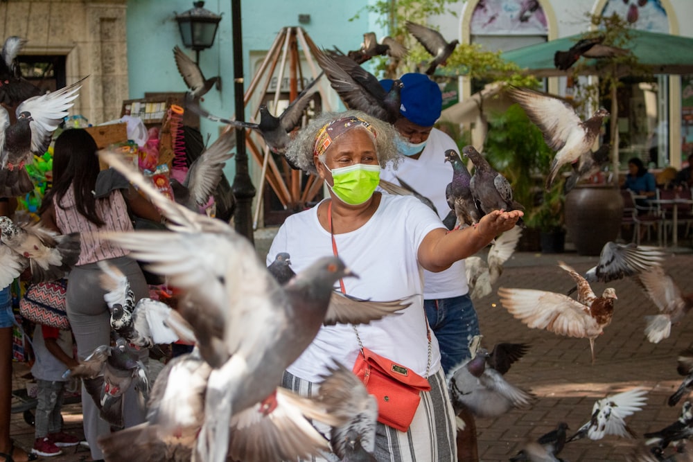 a woman with a tennis ball in her mouth surrounded by pigeons