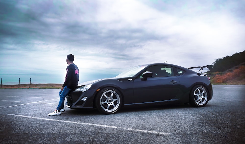 a man standing next to a car in a parking lot