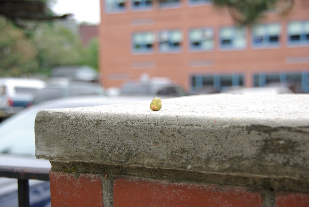 a small yellow object sitting on top of a cement wall