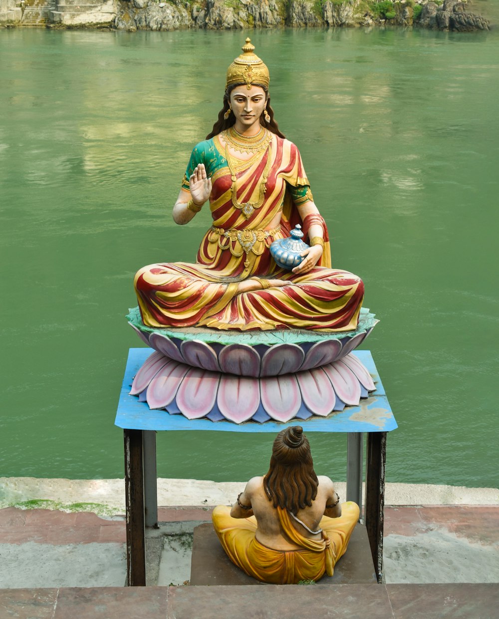 Una statua di un Buddha seduto in cima a un tavolo accanto a un corpo di