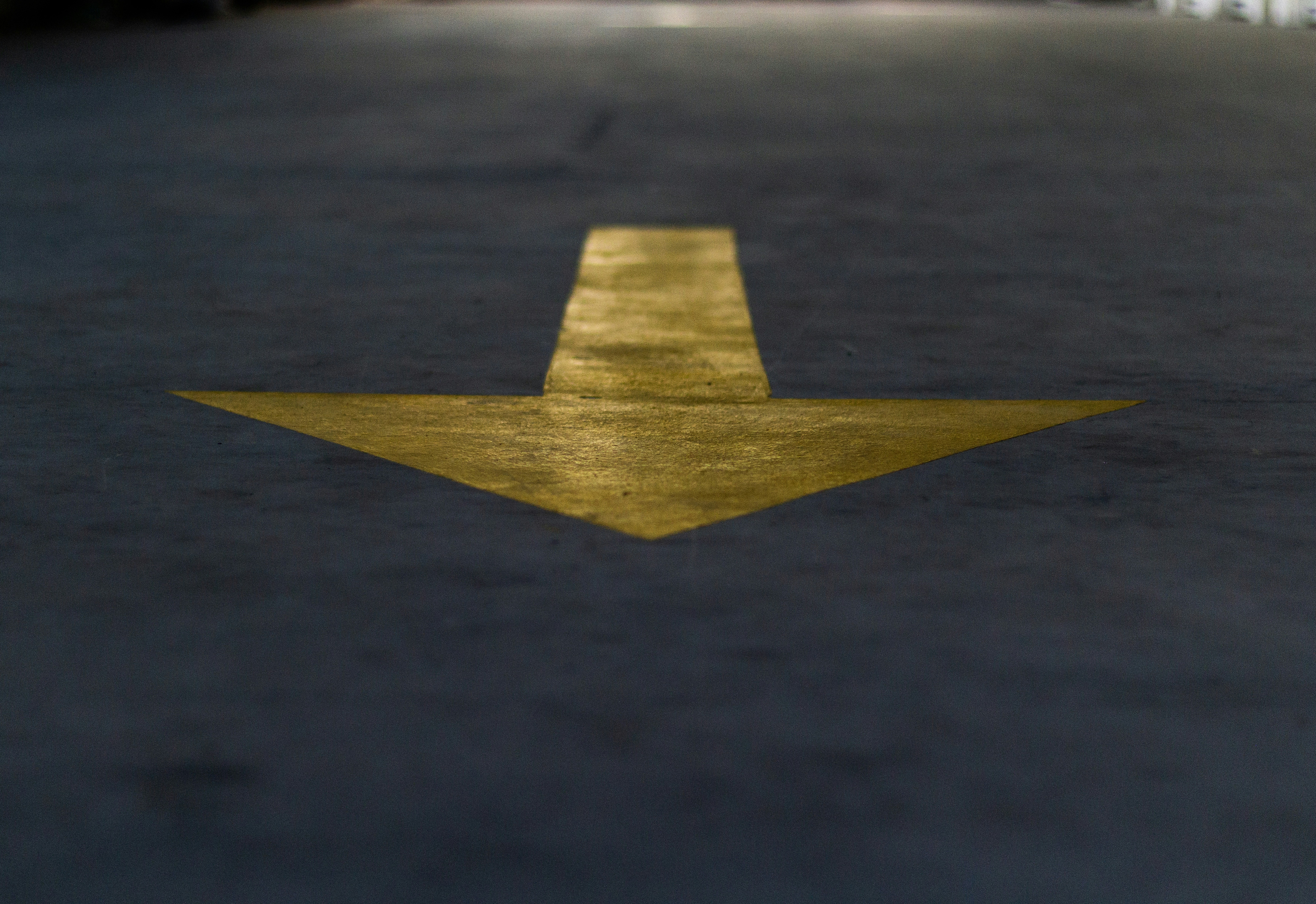a yellow arrow painted on the ground in a parking lot