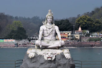 a statue of a lord shiv sitting on top of a rock