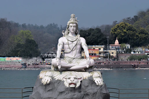 a statue of a lord shiv sitting on top of a rock