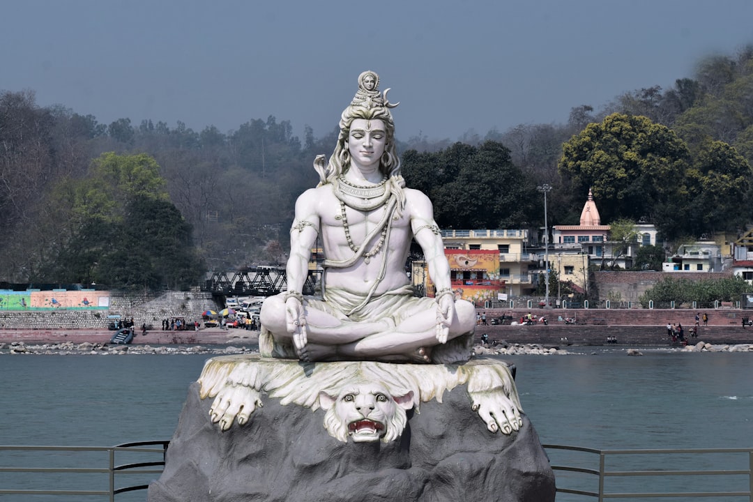 a statue of a person sitting on top of a rock, Mahadev as a yogi on the bank of the Ganga river.