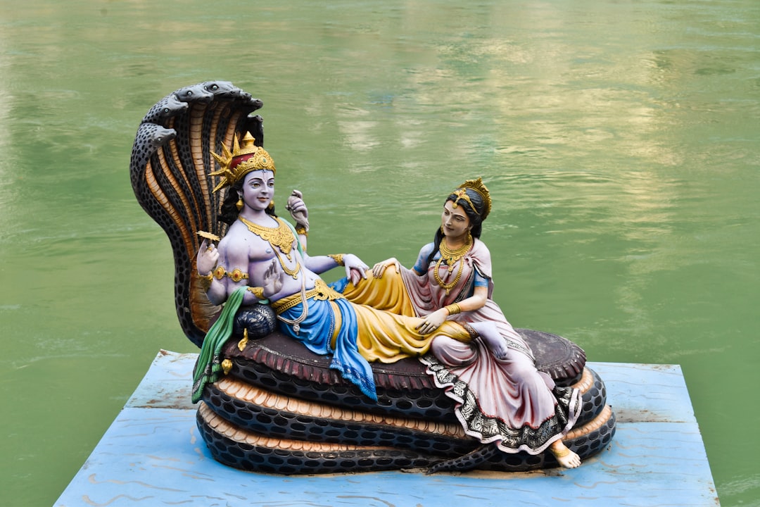 a statue of a woman sitting on top of a boat, Lord Vishnu and Goddess Lakshmi on the Aashan of Lord Sheshnag on the bank