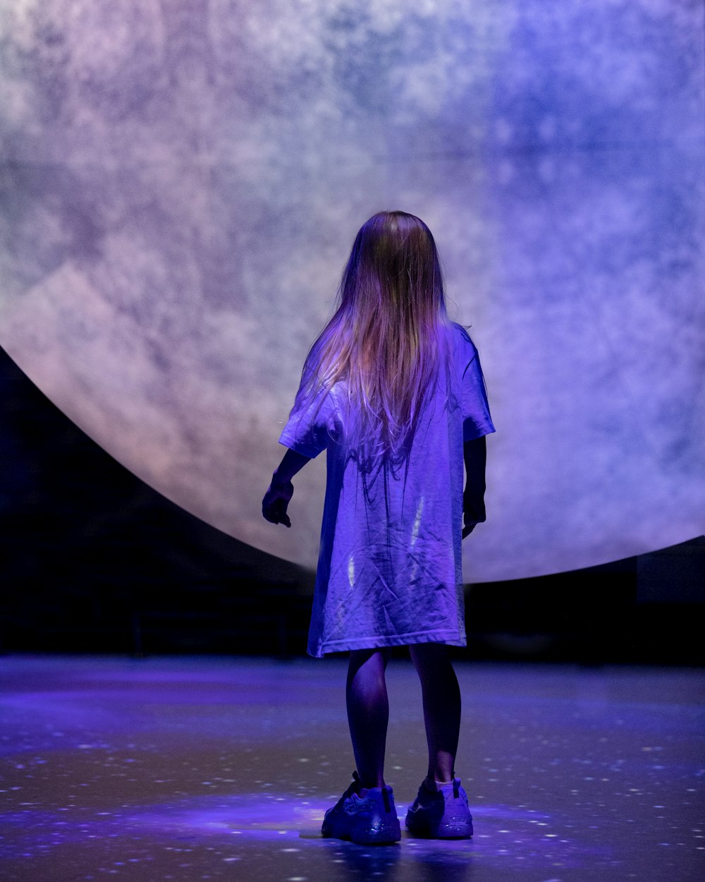 a woman standing in front of a giant moon