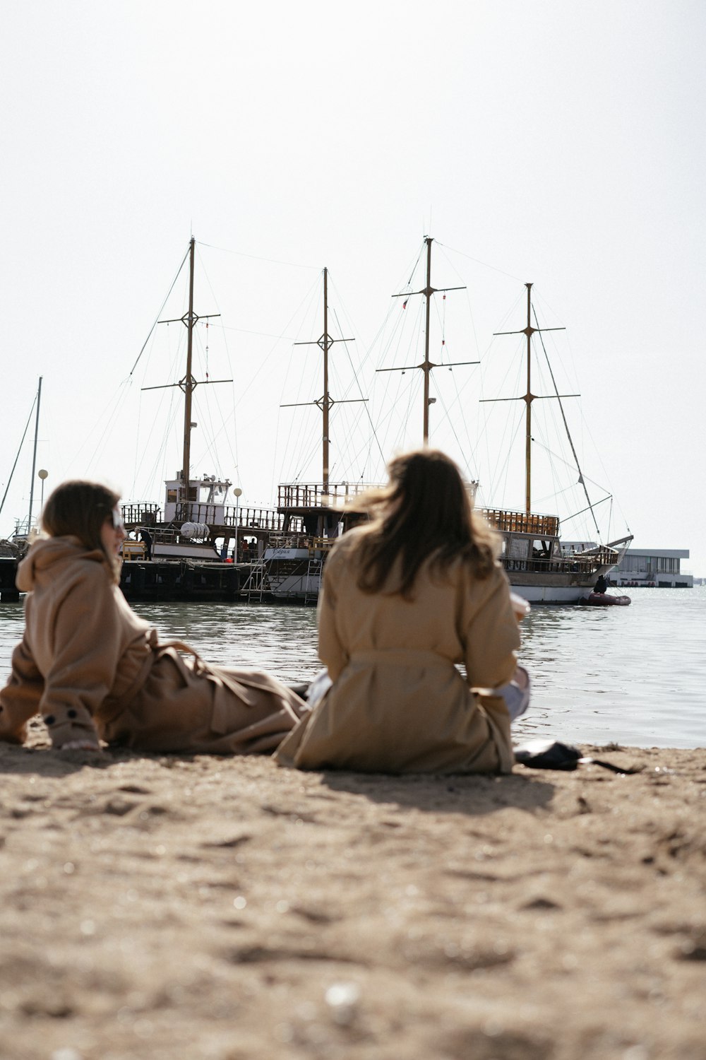 a couple of people sitting on top of a sandy beach