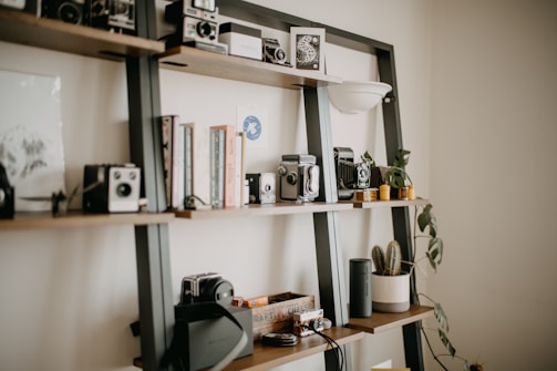 a shelf filled with cameras and books on top of a wall