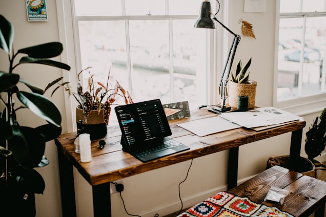 A cozy home office featuring a sleek fenoffs writing desk and an adjustable shelf bookcase filled with books and plants.