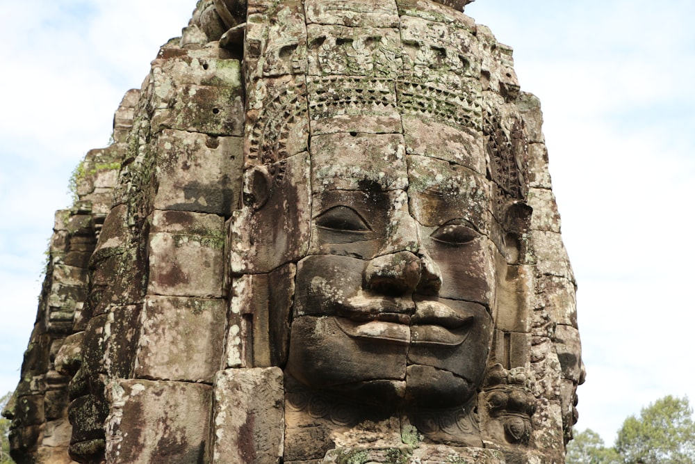 Una estatua de piedra de una cara con un árbol en el fondo