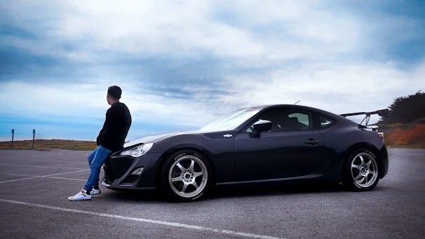 a man sitting on the hood of a sports car