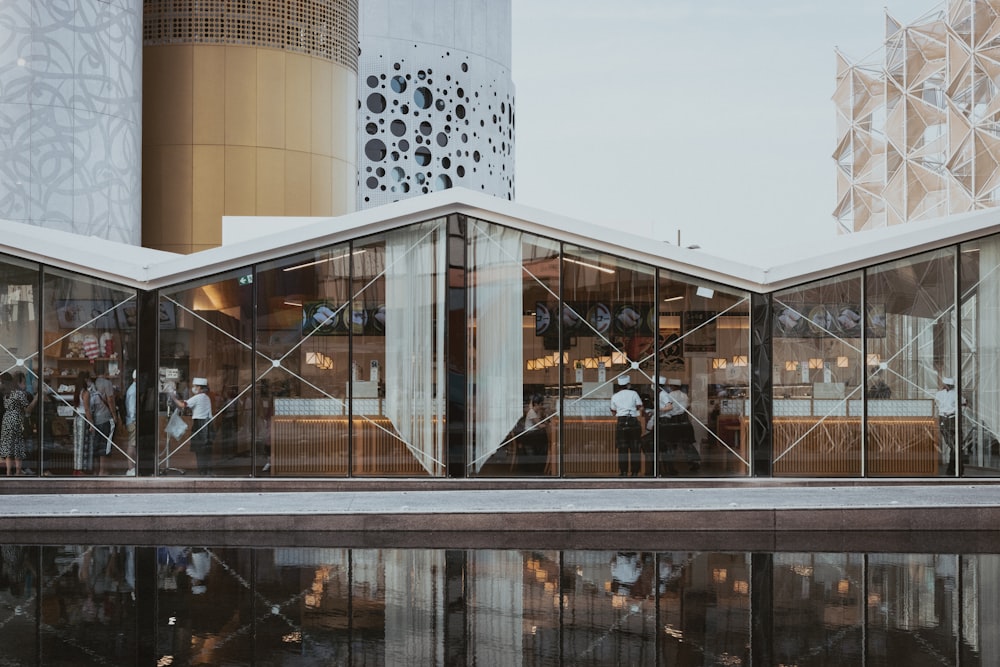 a group of people standing outside of a building next to a body of water