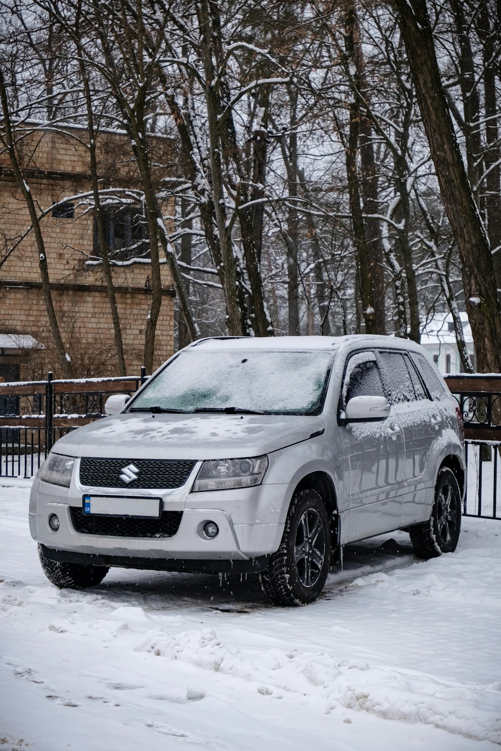 a white suv parked in the snow in front of a house