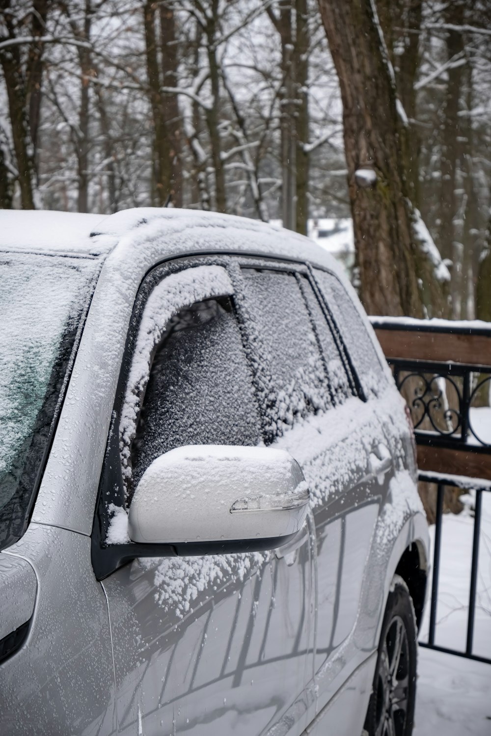 a car covered in snow parked in front of a fence