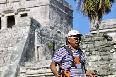 a man in a striped shirt and sunglasses standing in front of a castle