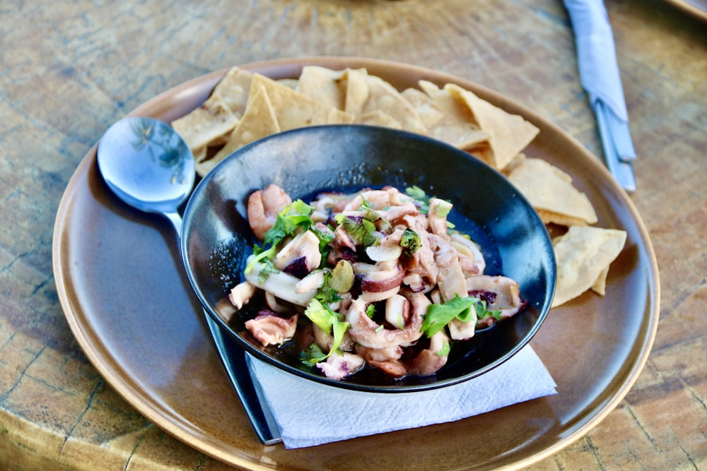 a bowl of food on a plate with chips