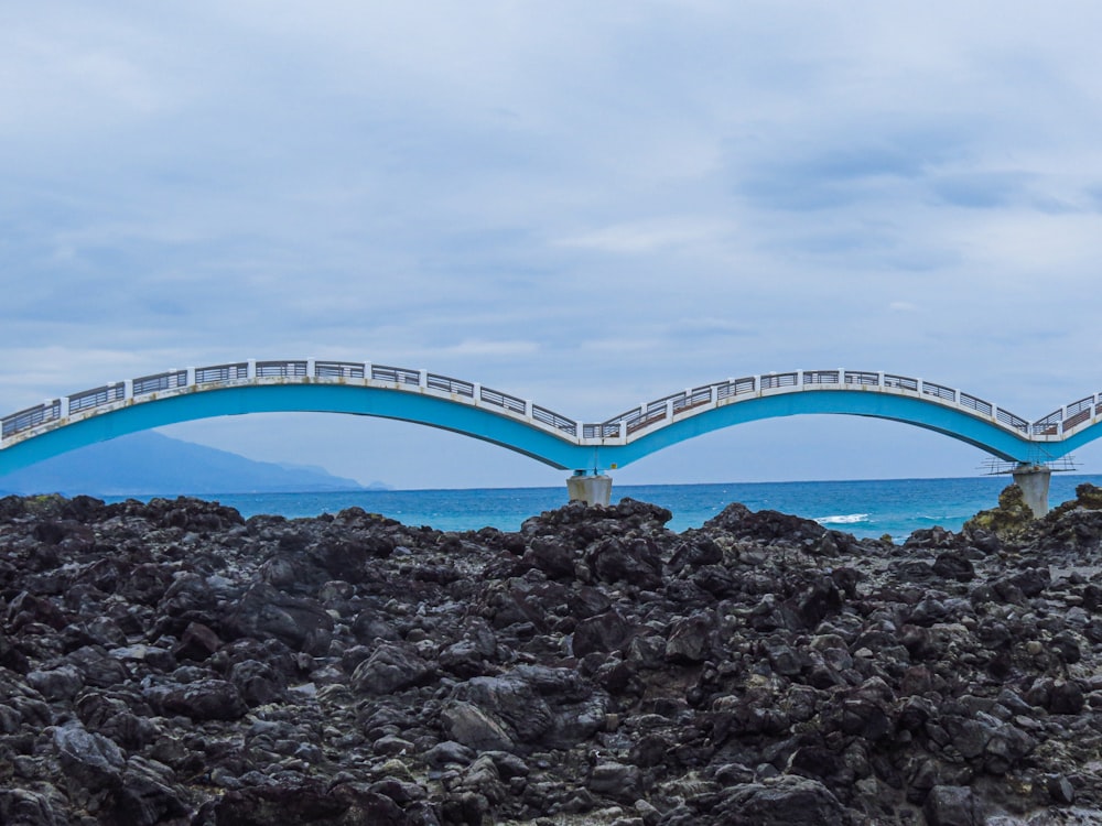 a bridge that is over some rocks by the ocean