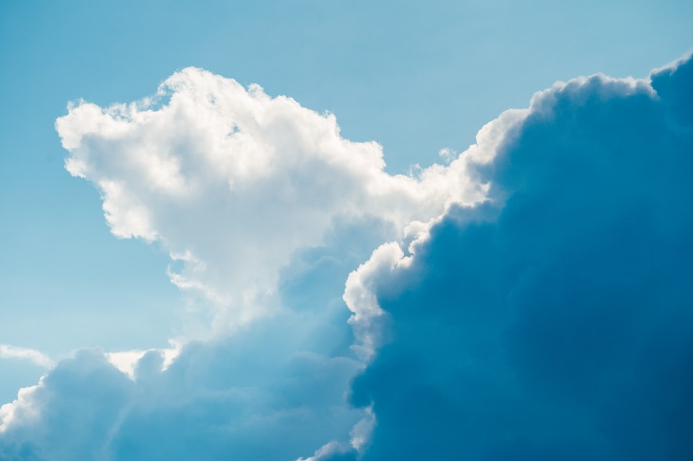 a plane flying through a cloudy blue sky