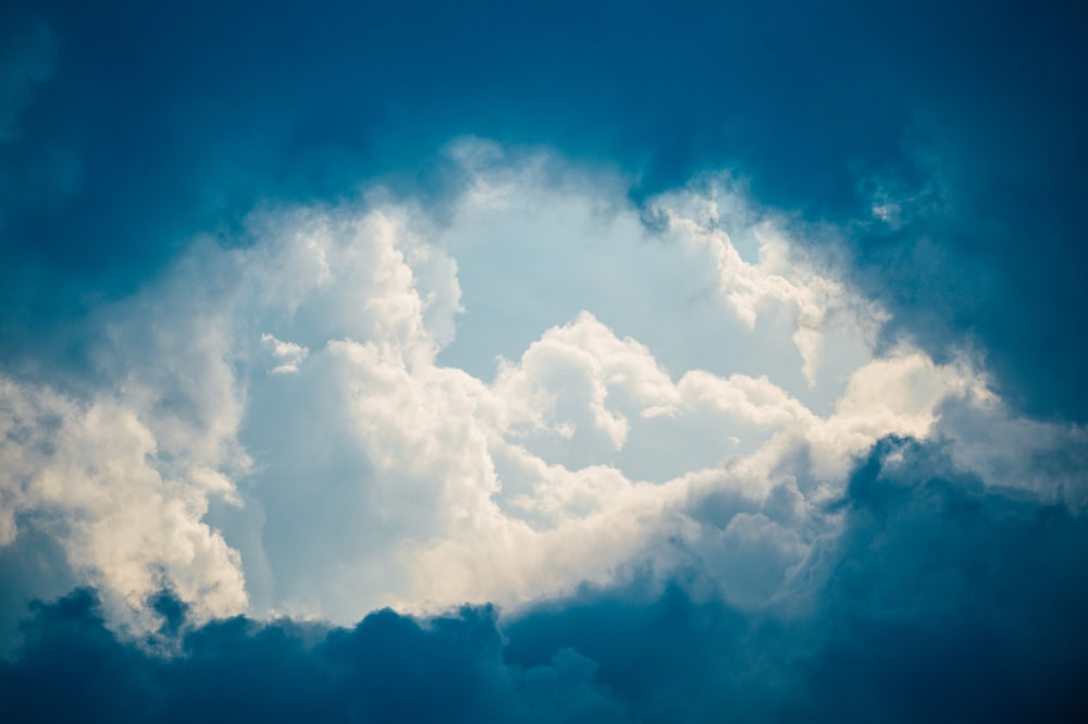 a plane flying through a cloudy blue sky