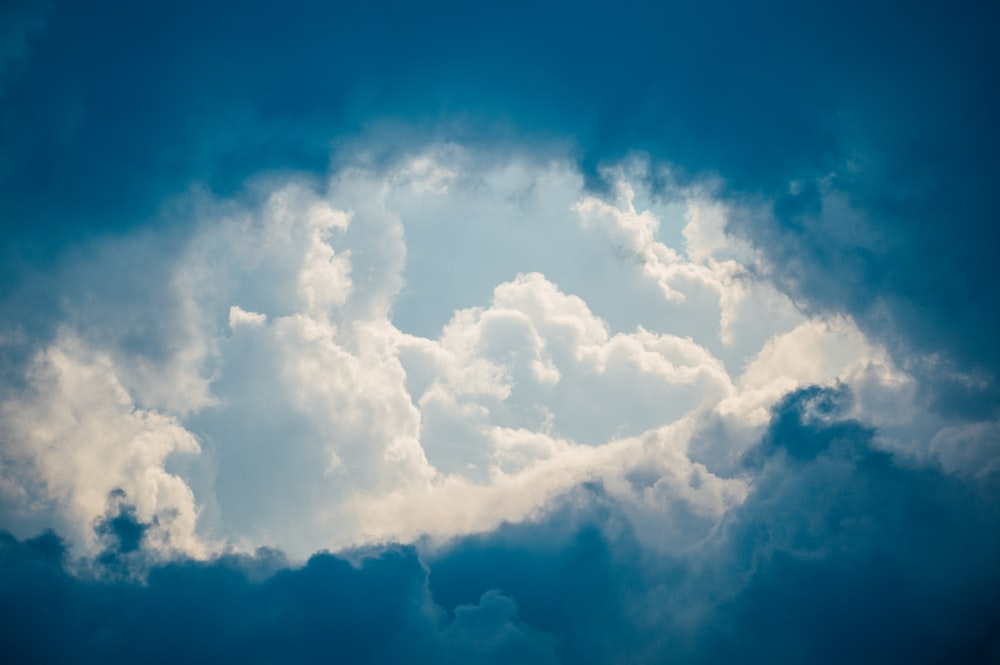 a plane flying through a cloudy blue sky