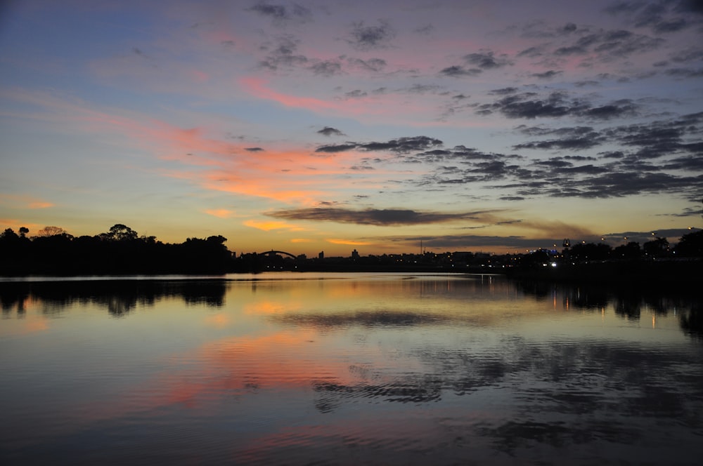 Un tramonto su uno specchio d'acqua con nuvole nel cielo