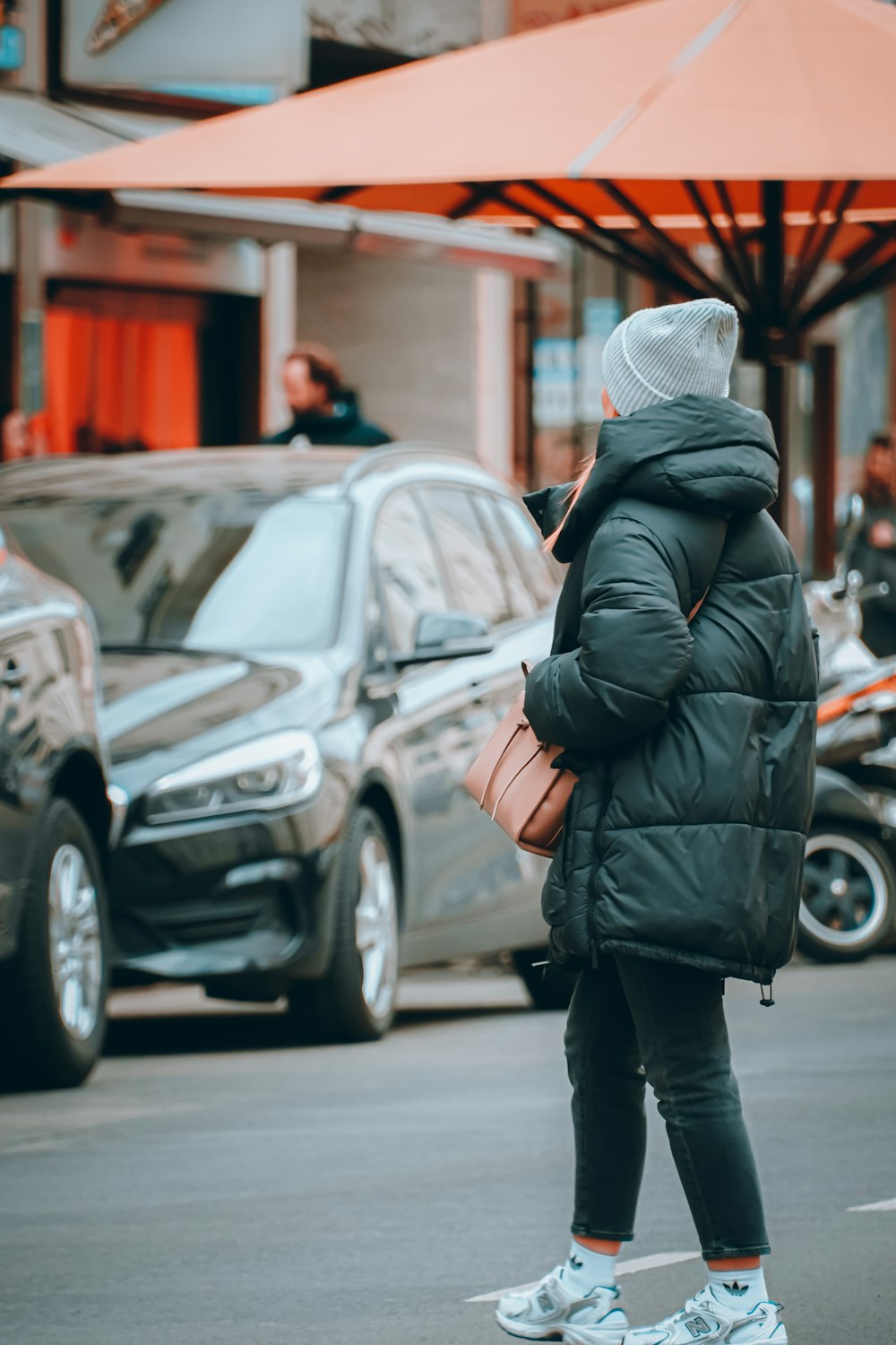 a woman walking down the street in front of a car