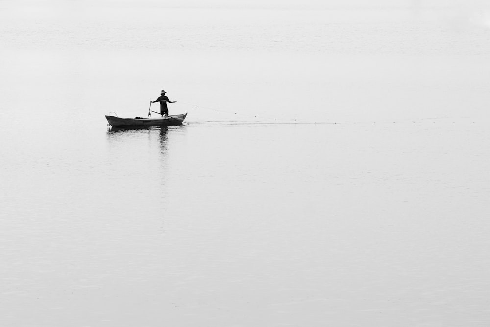 a man standing on a boat in the middle of a lake
