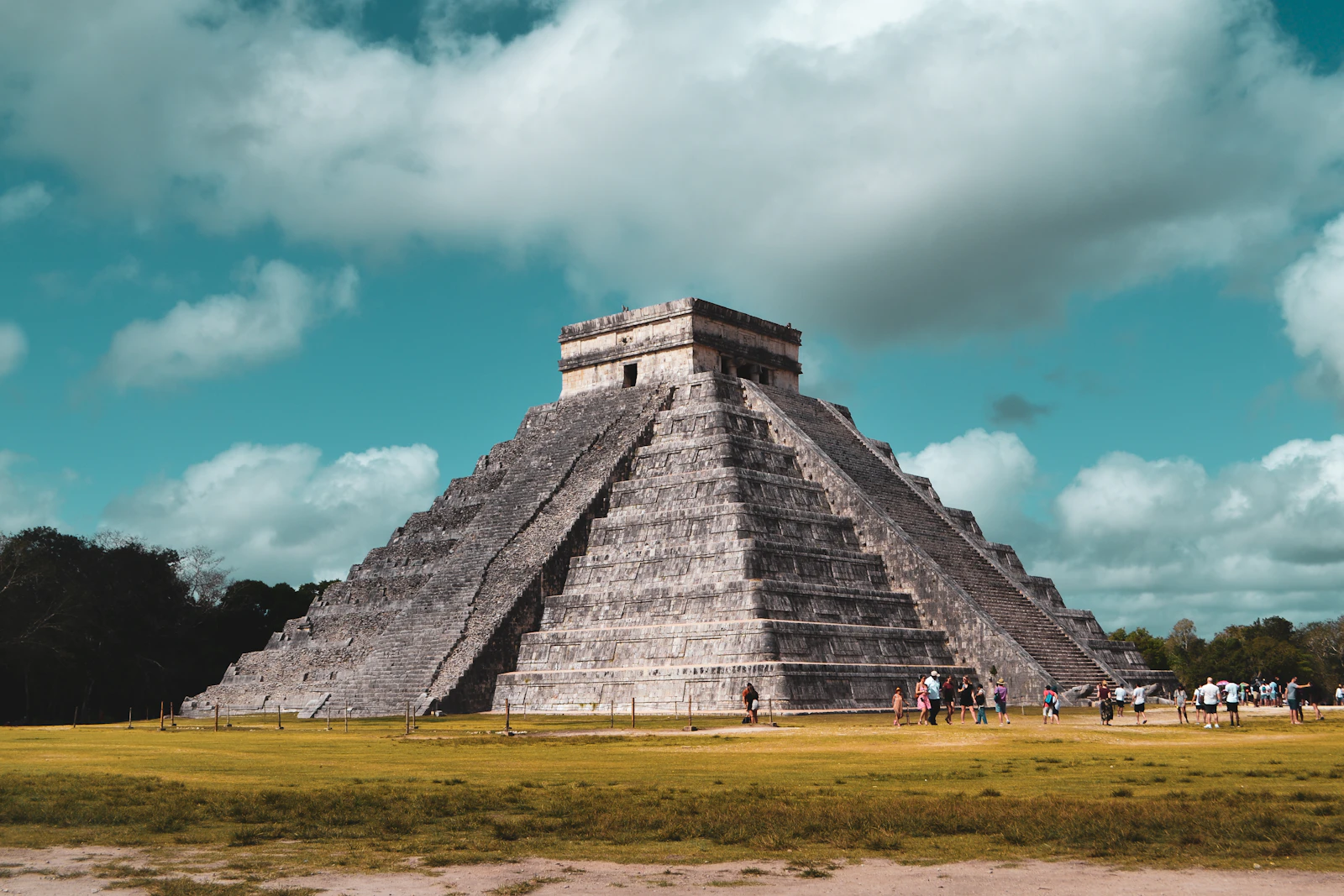 Visitors standing before the stepped pyramid at Chichén Itzá