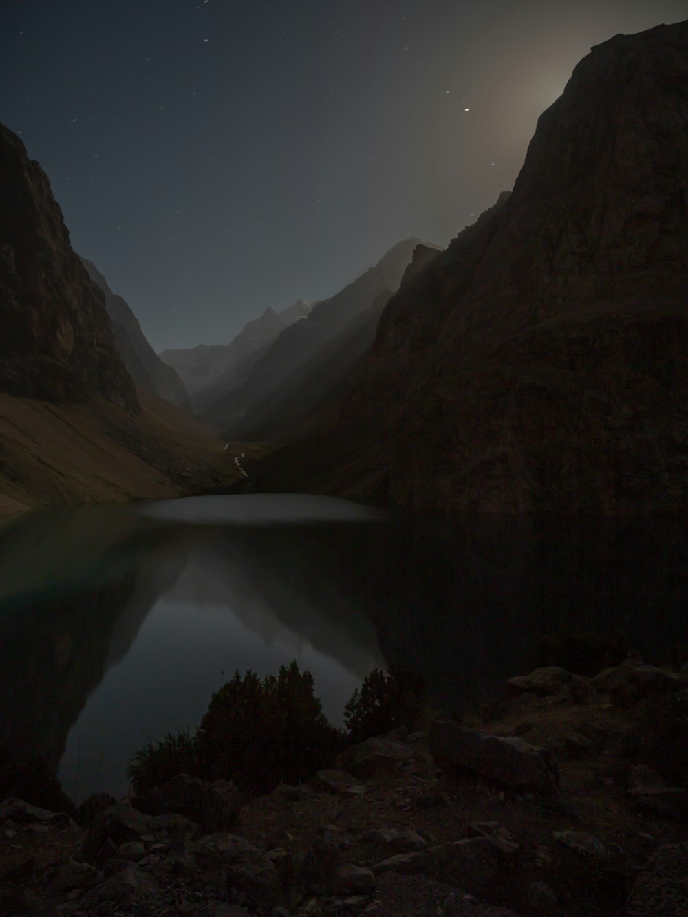 a full moon shines over a mountain lake