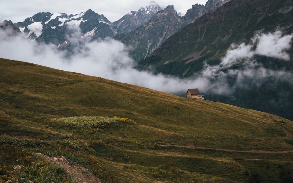 a house on a grassy hill with mountains in the background