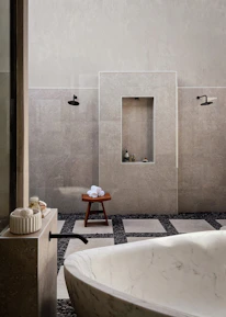 Wide shot of a minimalist bathroom featuring elegant tile and stone work in soft greys.