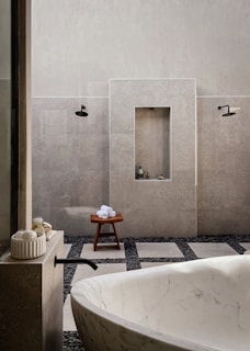 Minimalist bathroom featuring a dark-toned marble washbasin with subtle leaf patterns