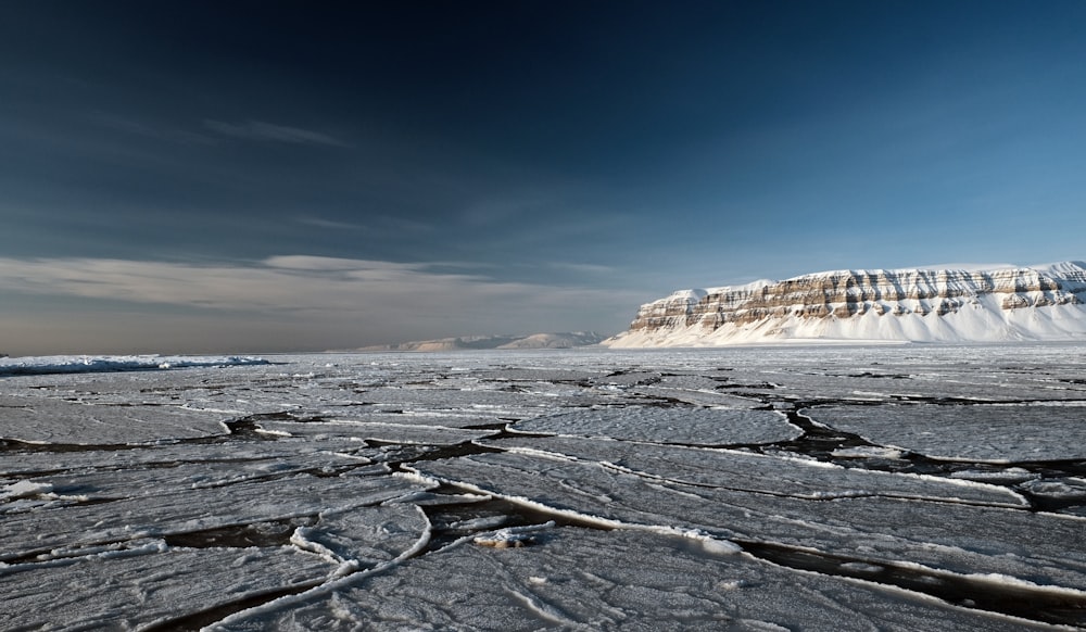 a large expanse of ice with a mountain in the background