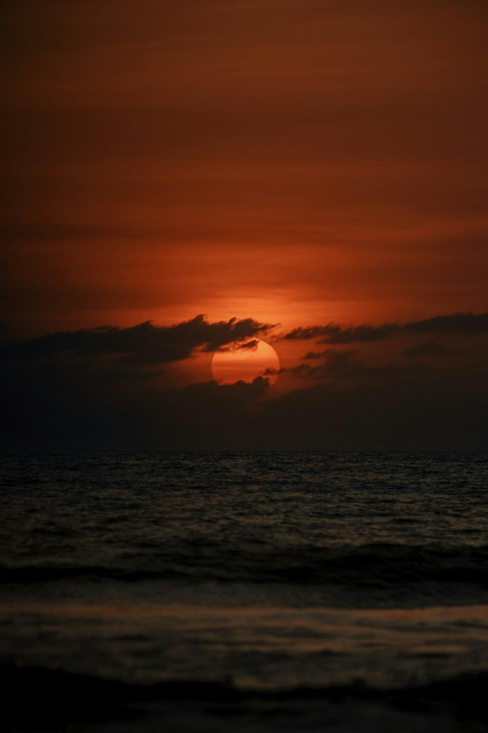 the sun is setting over the ocean on a cloudy day