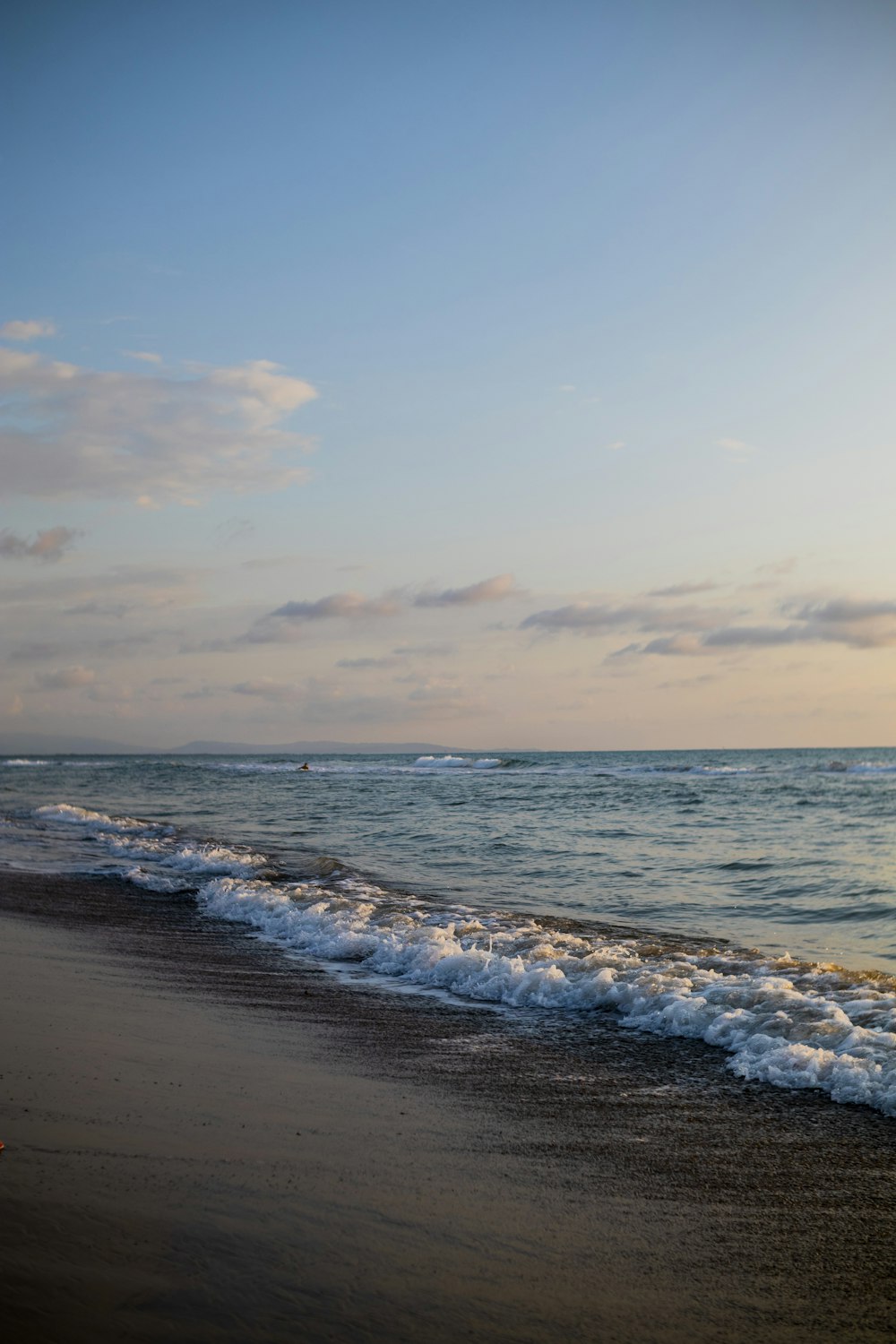 a person walking on the beach with a surfboard