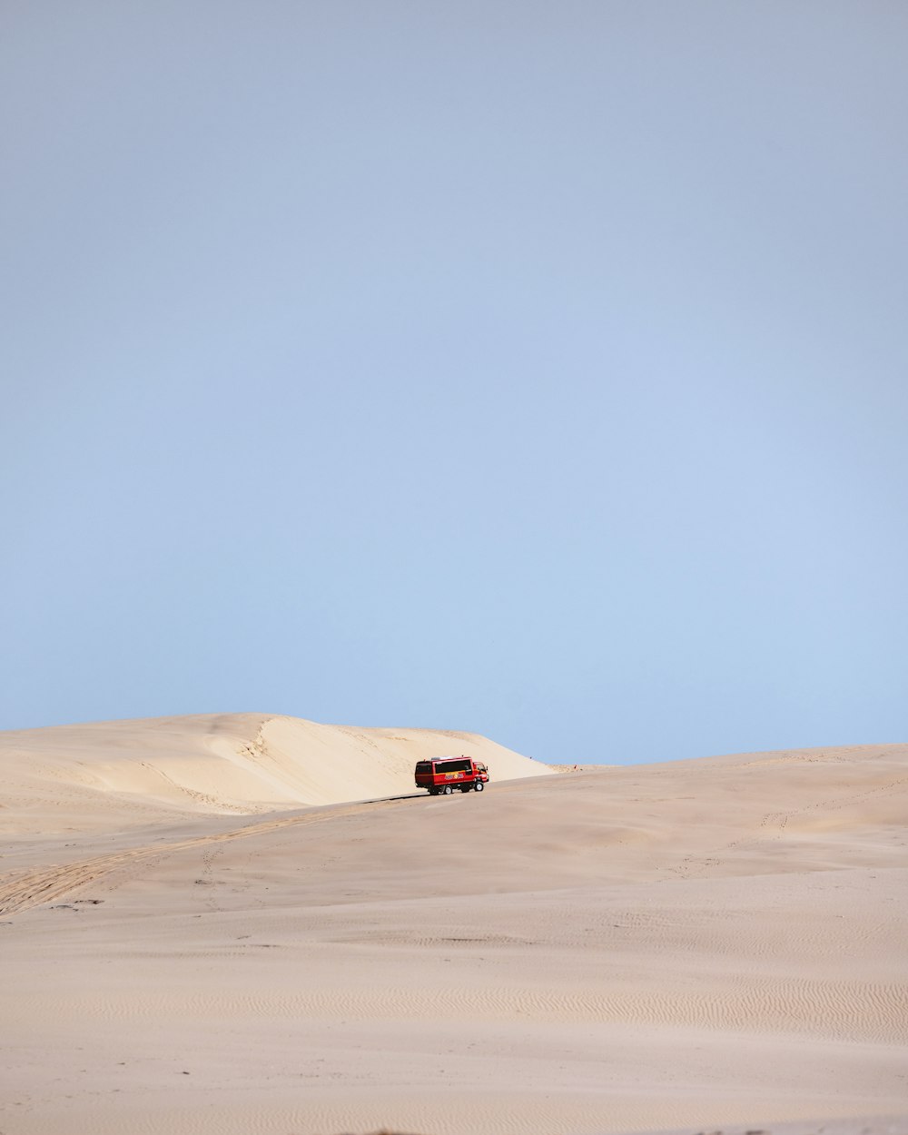 a red truck driving through a sandy desert