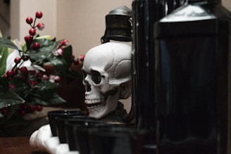 a skull statue sitting on top of a table next to a bottle