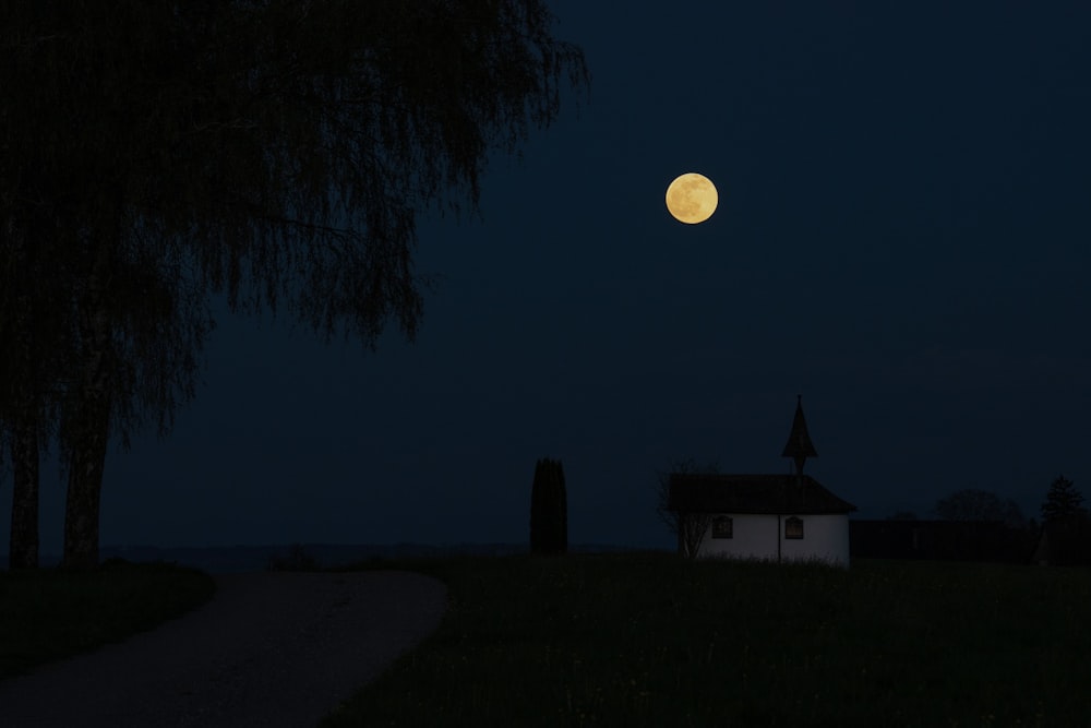 a house in a field with a full moon in the background