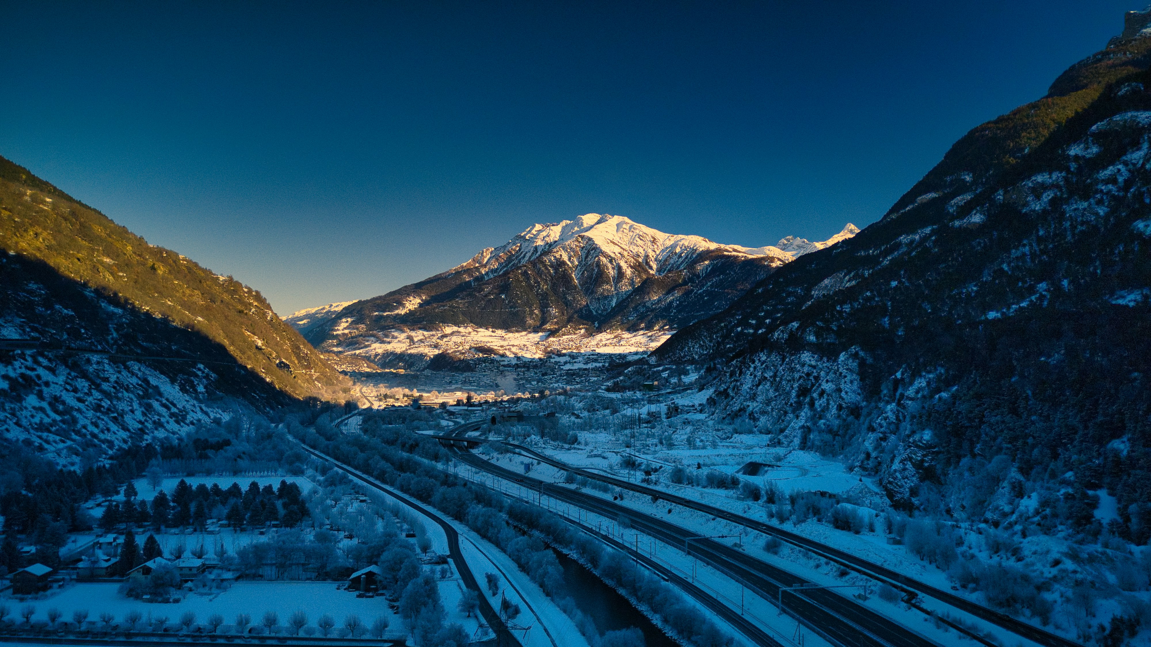 a train traveling through a snow covered mountain valley