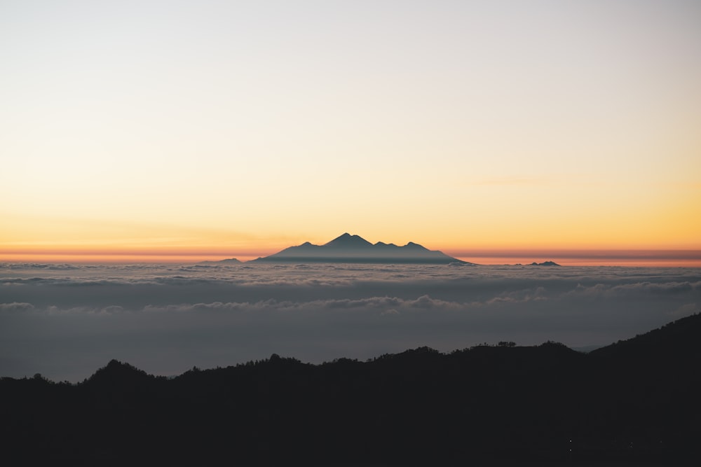 a view of a mountain in the distance above the clouds