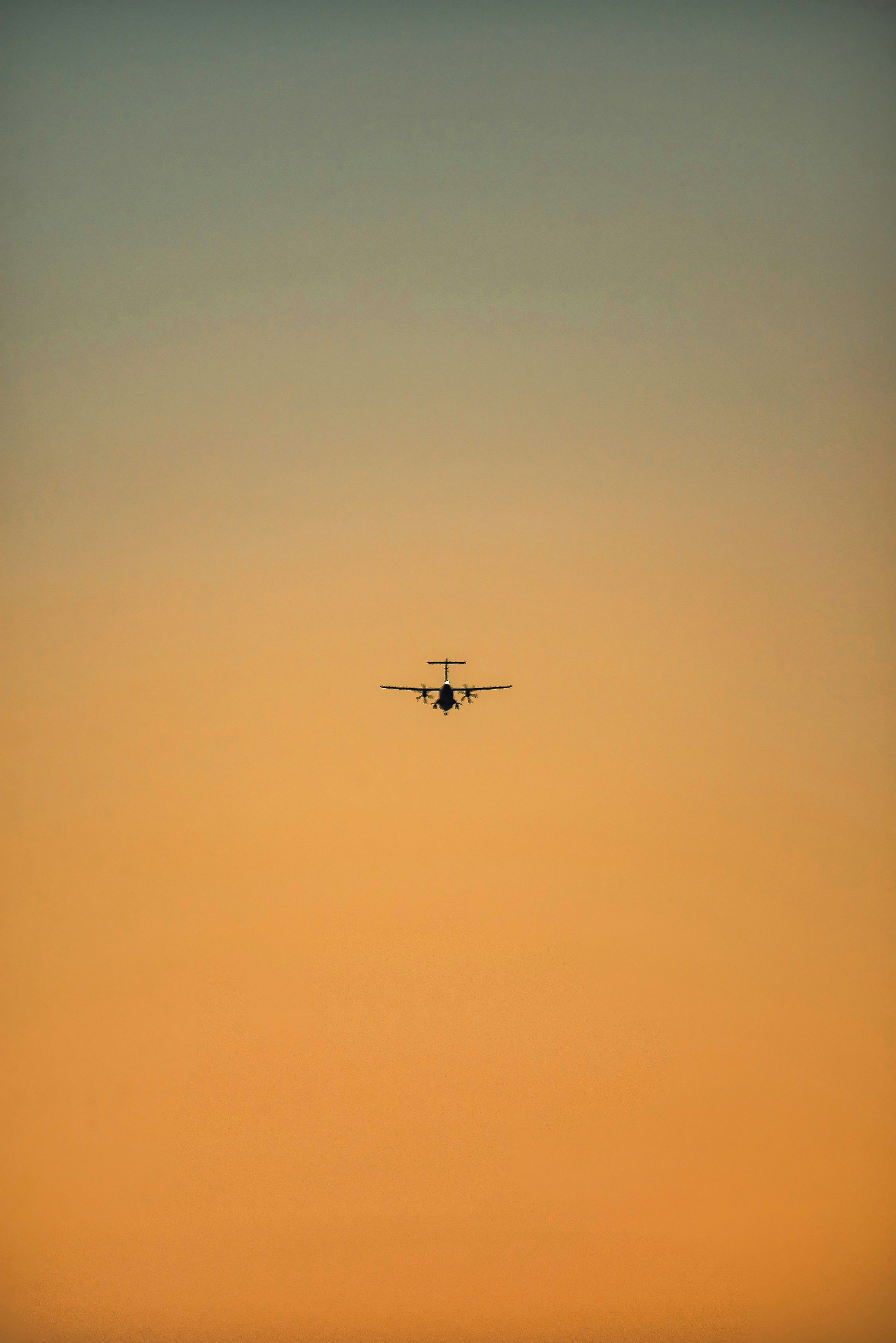 a plane flying in the sky at sunset