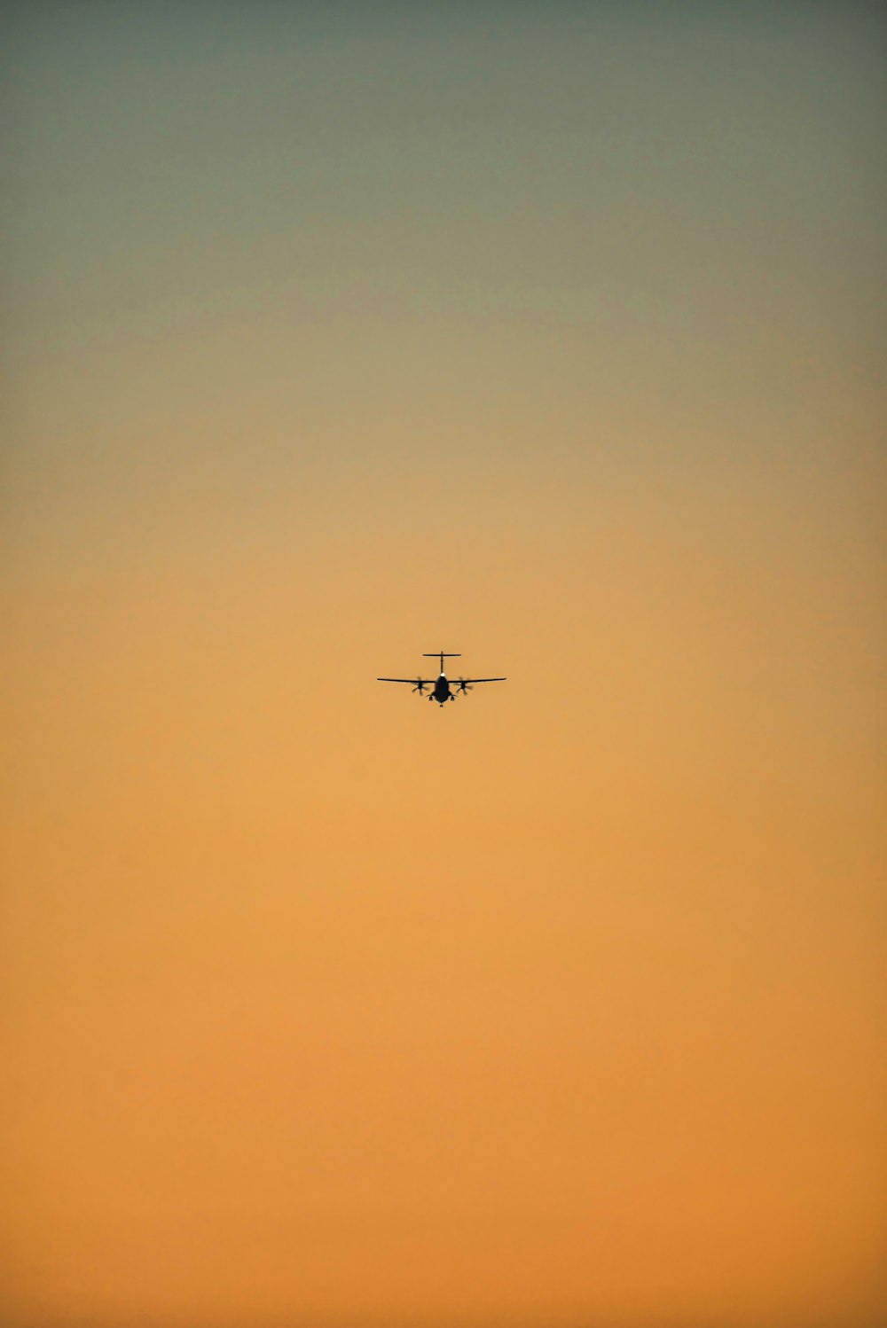 a plane flying in the sky at sunset