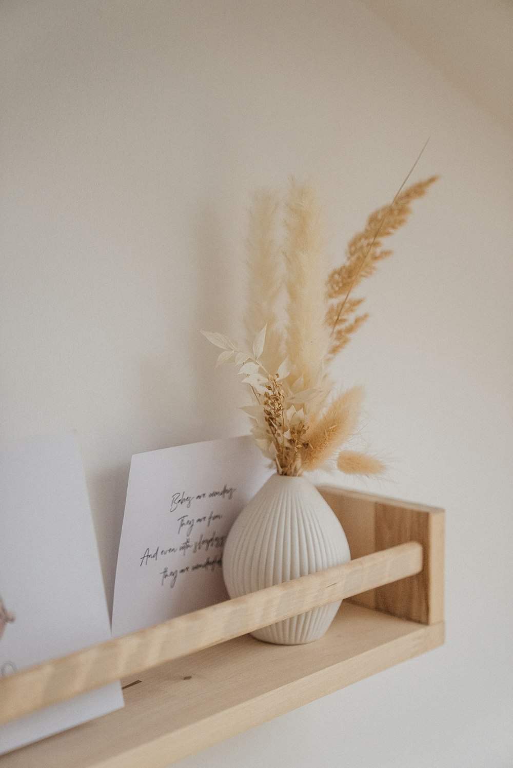 a white vase sitting on top of a wooden shelf